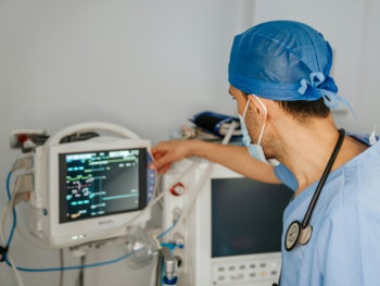 a man in scrubs and a stethoscope looking at a monitor